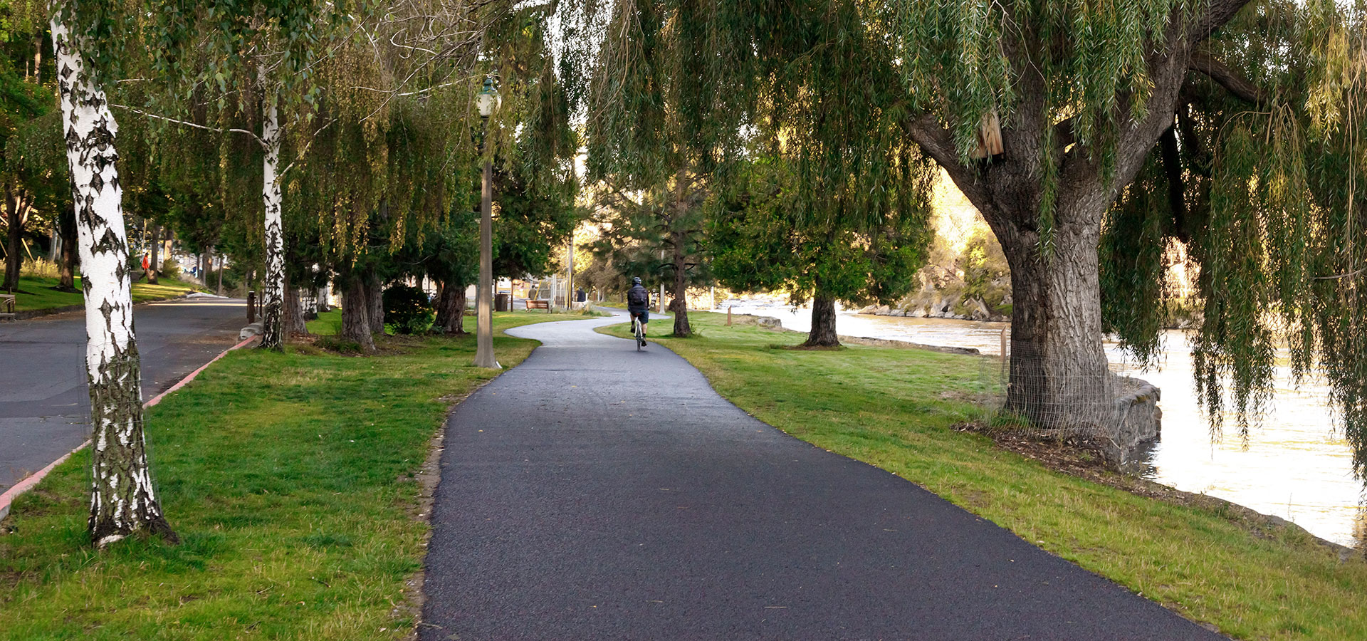 Asphalt path along the grassy riverbank at Pacific Park