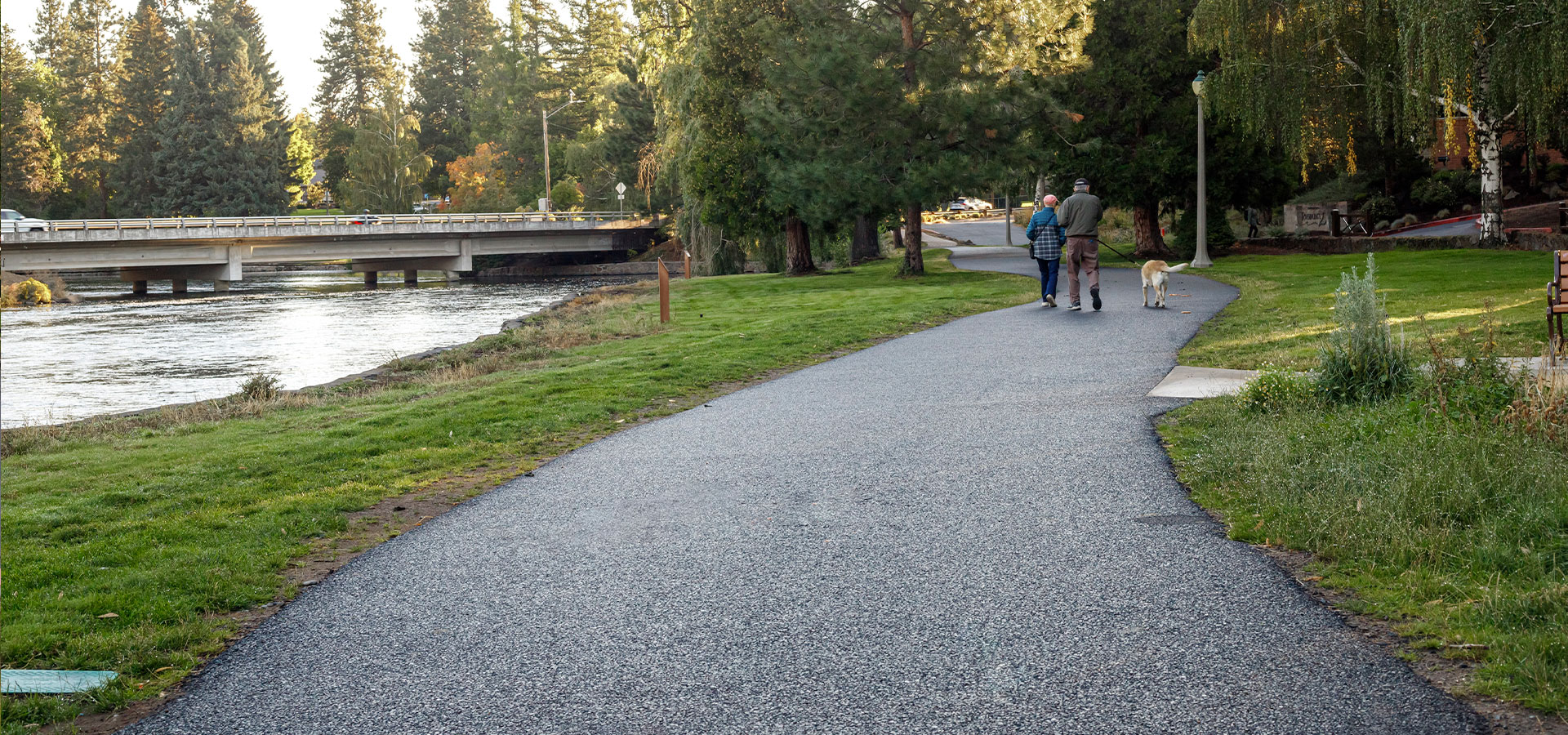 Couple with their dog walk on the asphalt path at Pacific Park