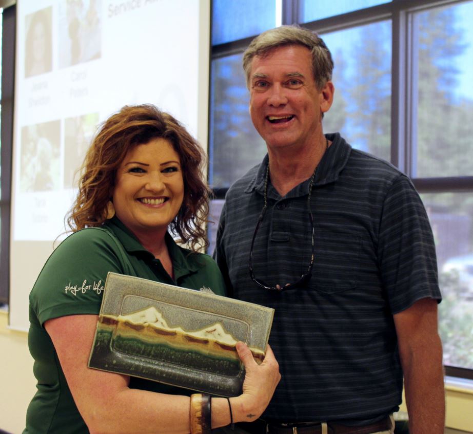 Employee holding award with director for years of service.