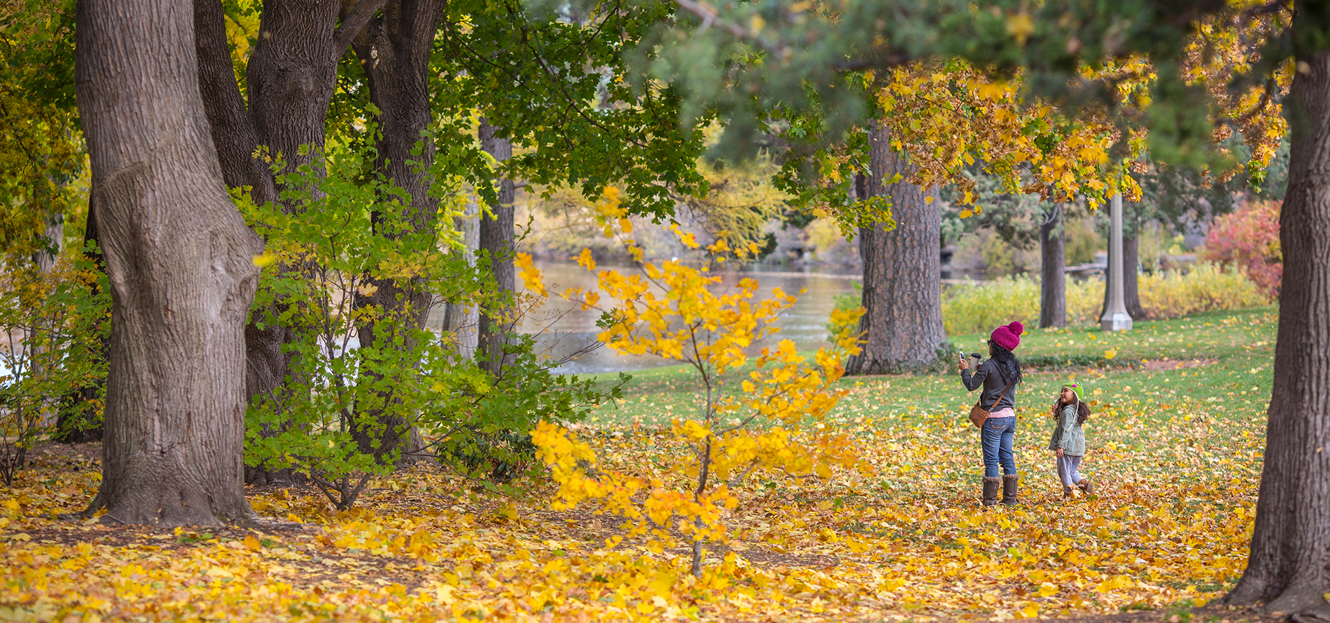 A mom and daughter taking photos of the fall leaves in Drake Park.