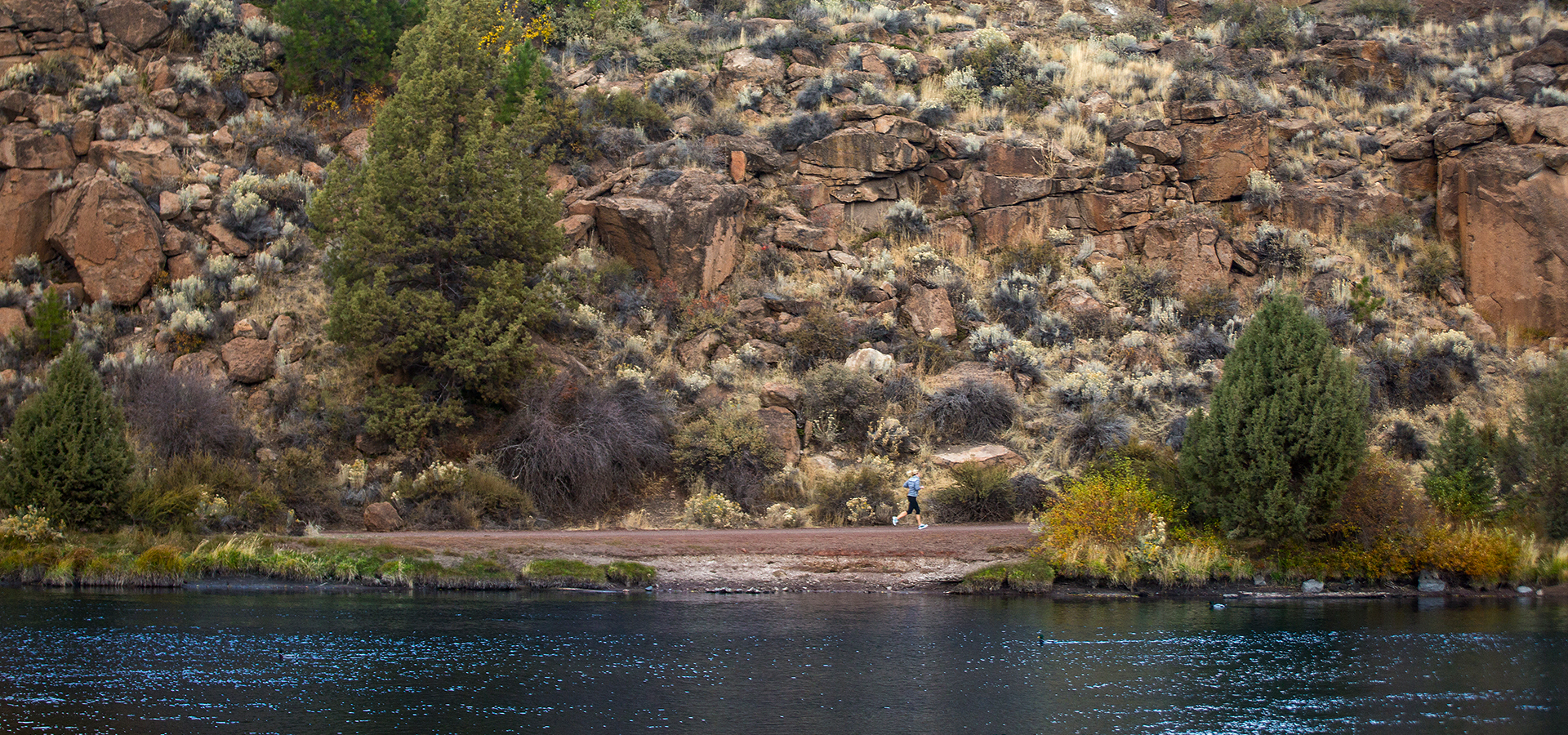 The deschutes river with a running path in the distance.
