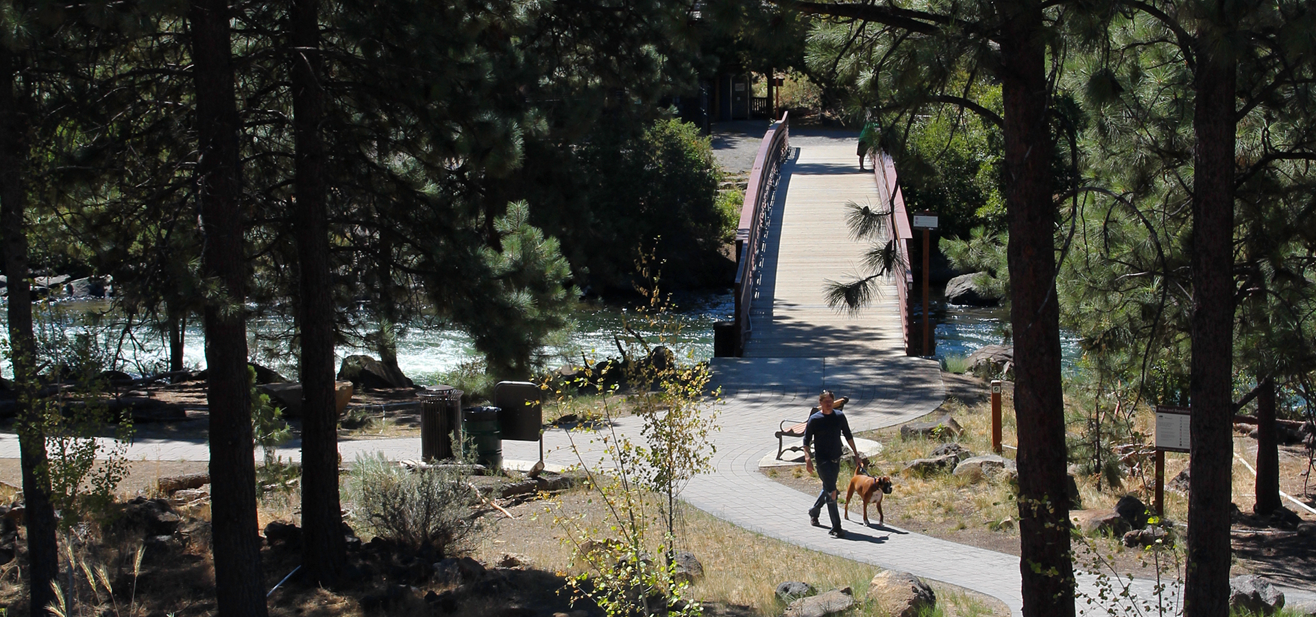 A man walking a dog at first street rapids park.
