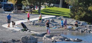 People standing on the banks of the Deschutes River at McKay Park.