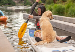 Image of a patron and her dog using the wet ramp to launch their paddle board.