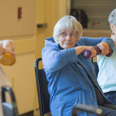 older adults lifting small weights in a class.