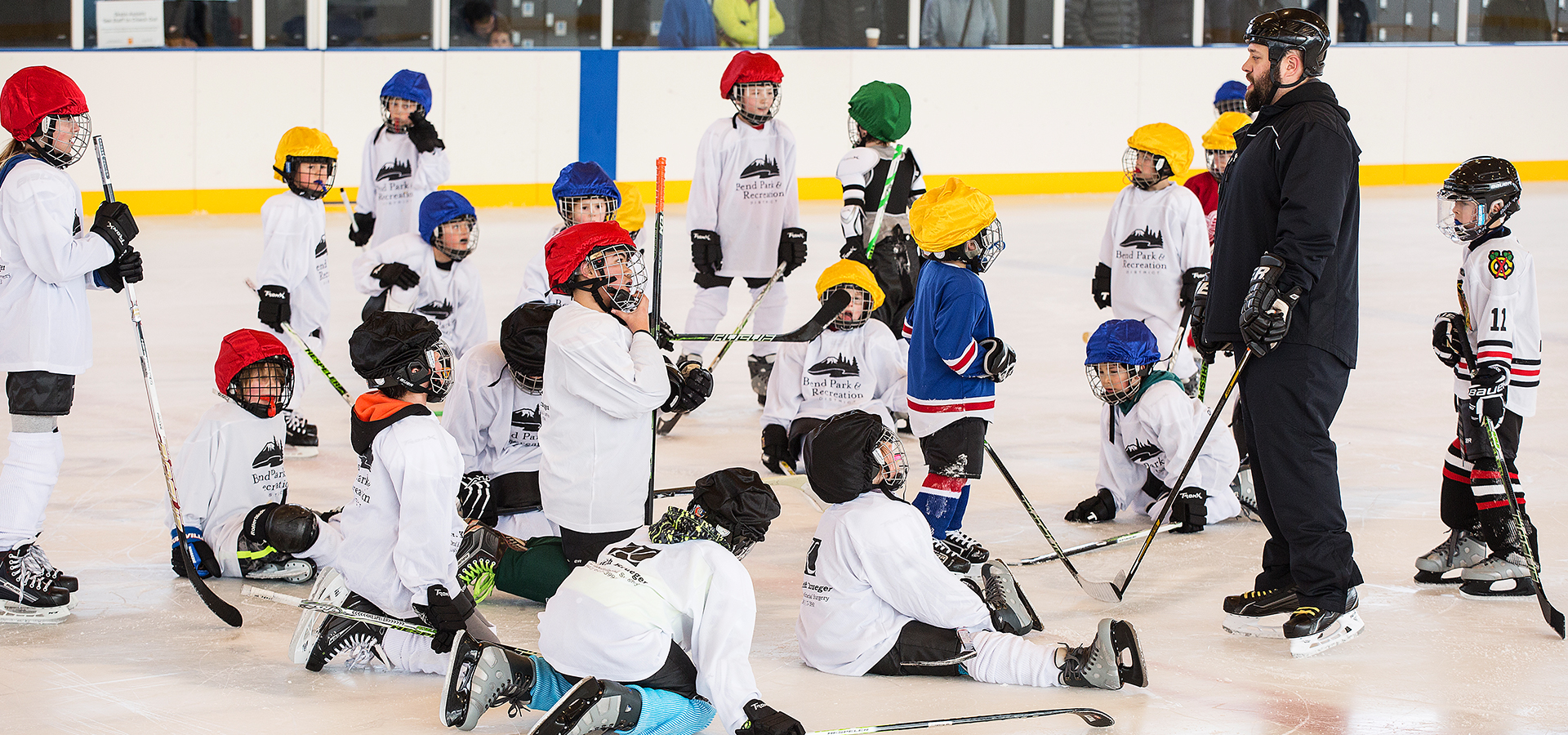 A coach talking to young hockey players at practice.