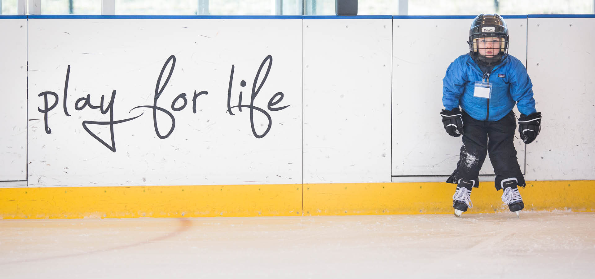 little kid standing on hockey skates in the rink