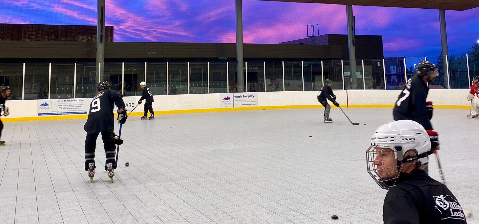A group of adults practice roller hockey during sunset at the Pavilion.