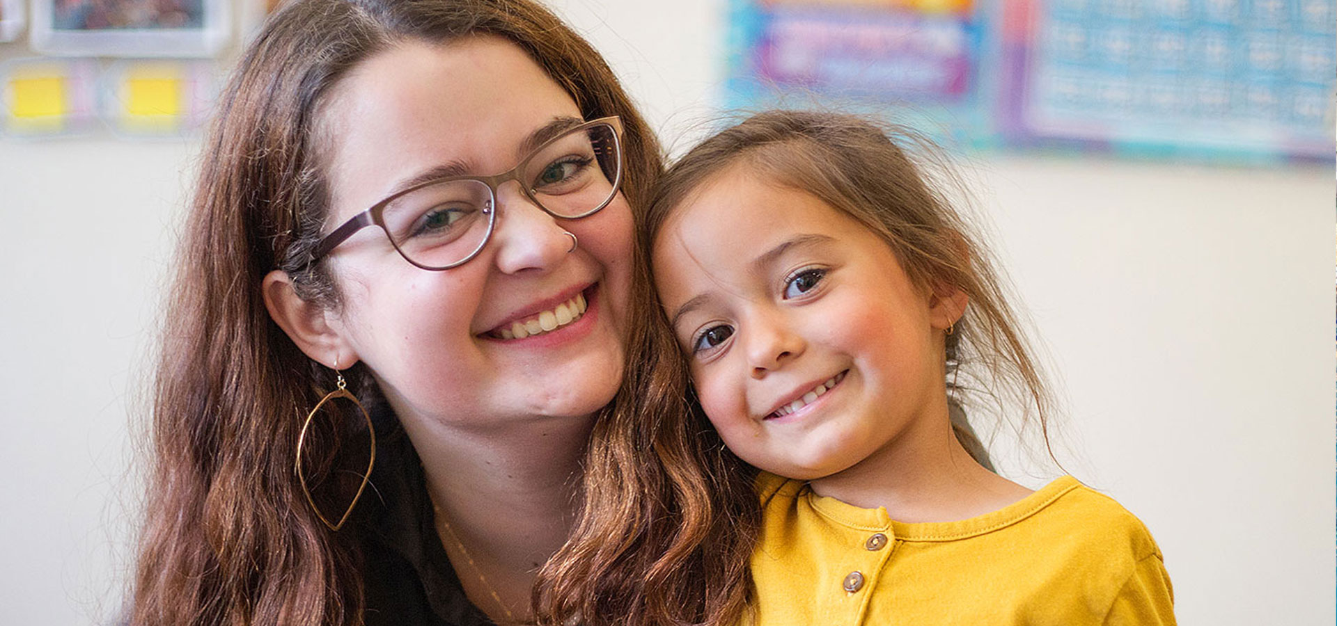 A BPRD childcare employee smiles with a young child.