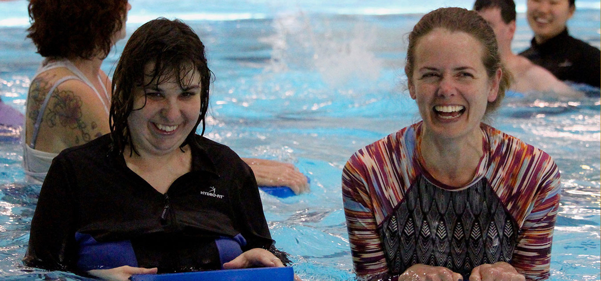 A theraeutic recreation instruction smiles with a patron in the pool.