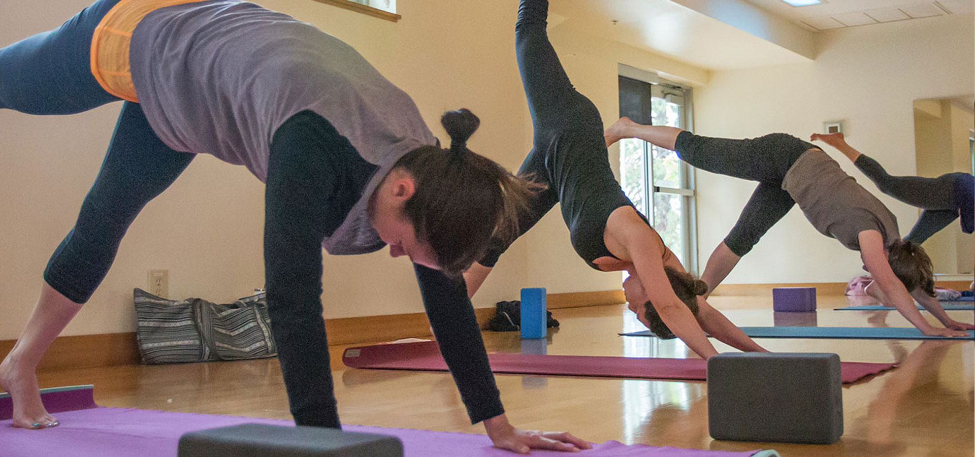 Several patrons holding yoga poses during a fitness class.