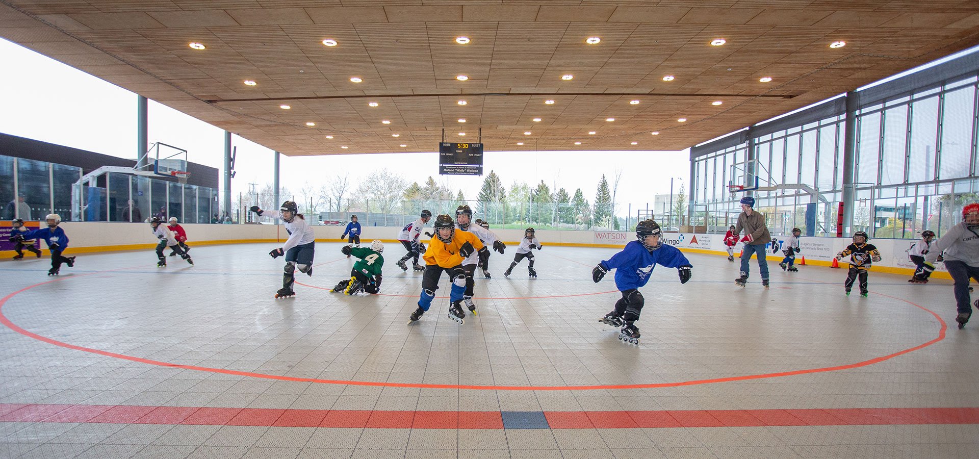 Class of children practiicng their moves during rolelr hockey practice.