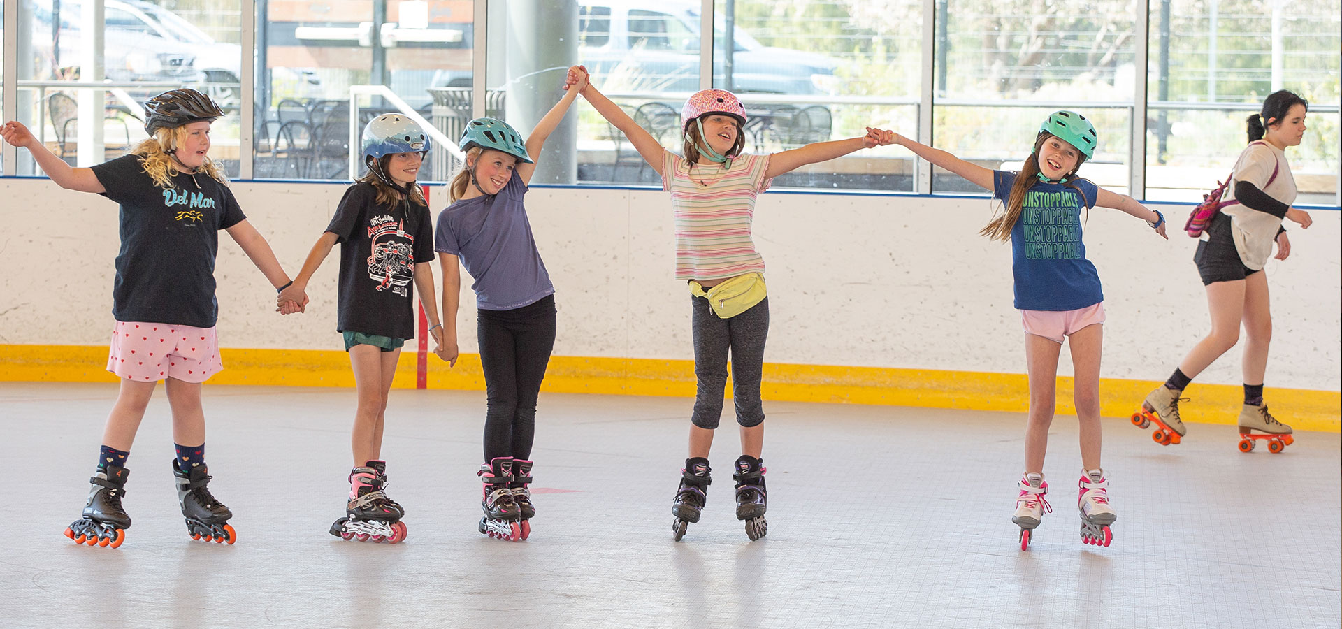 Group of five girls holding hands while enjoying roller sakting at hte Pavilion