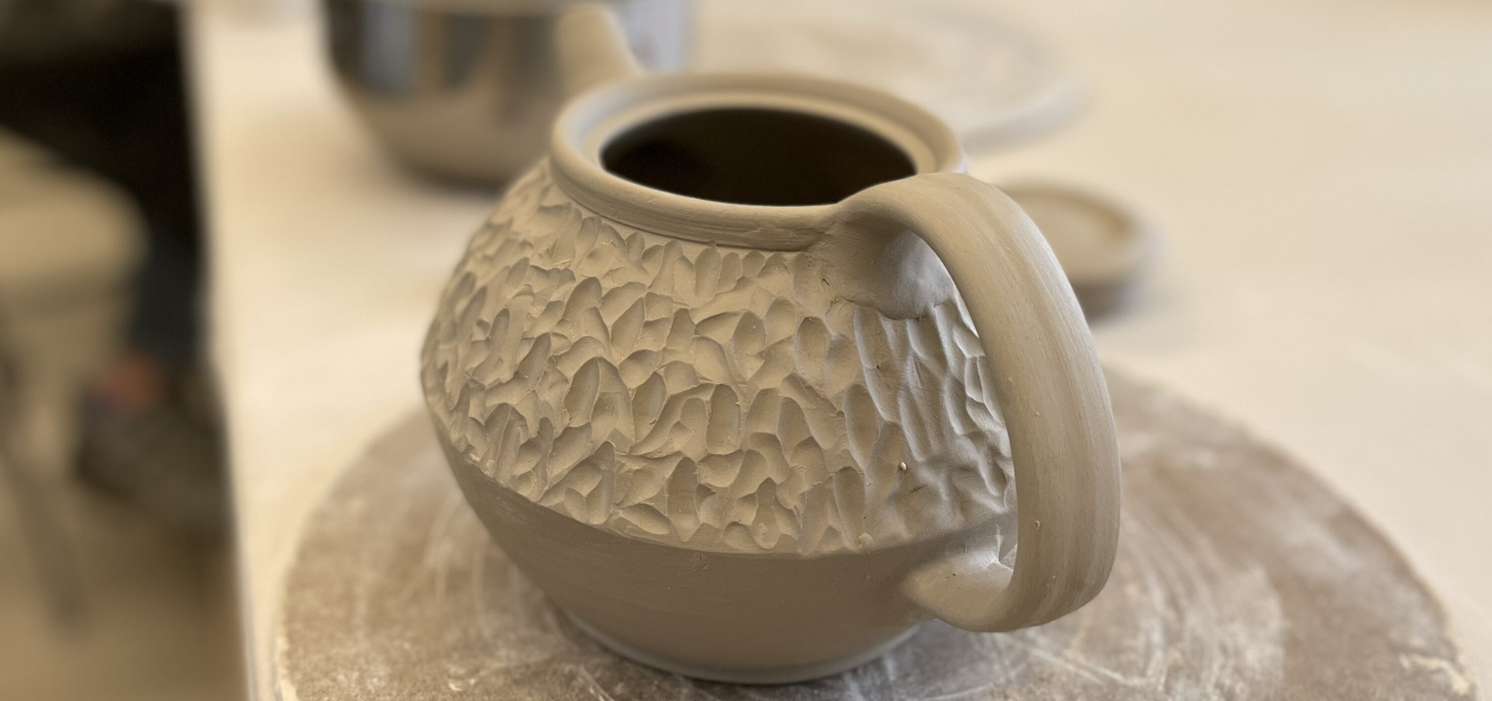 an unfinished clay tea pot waiting to be painted