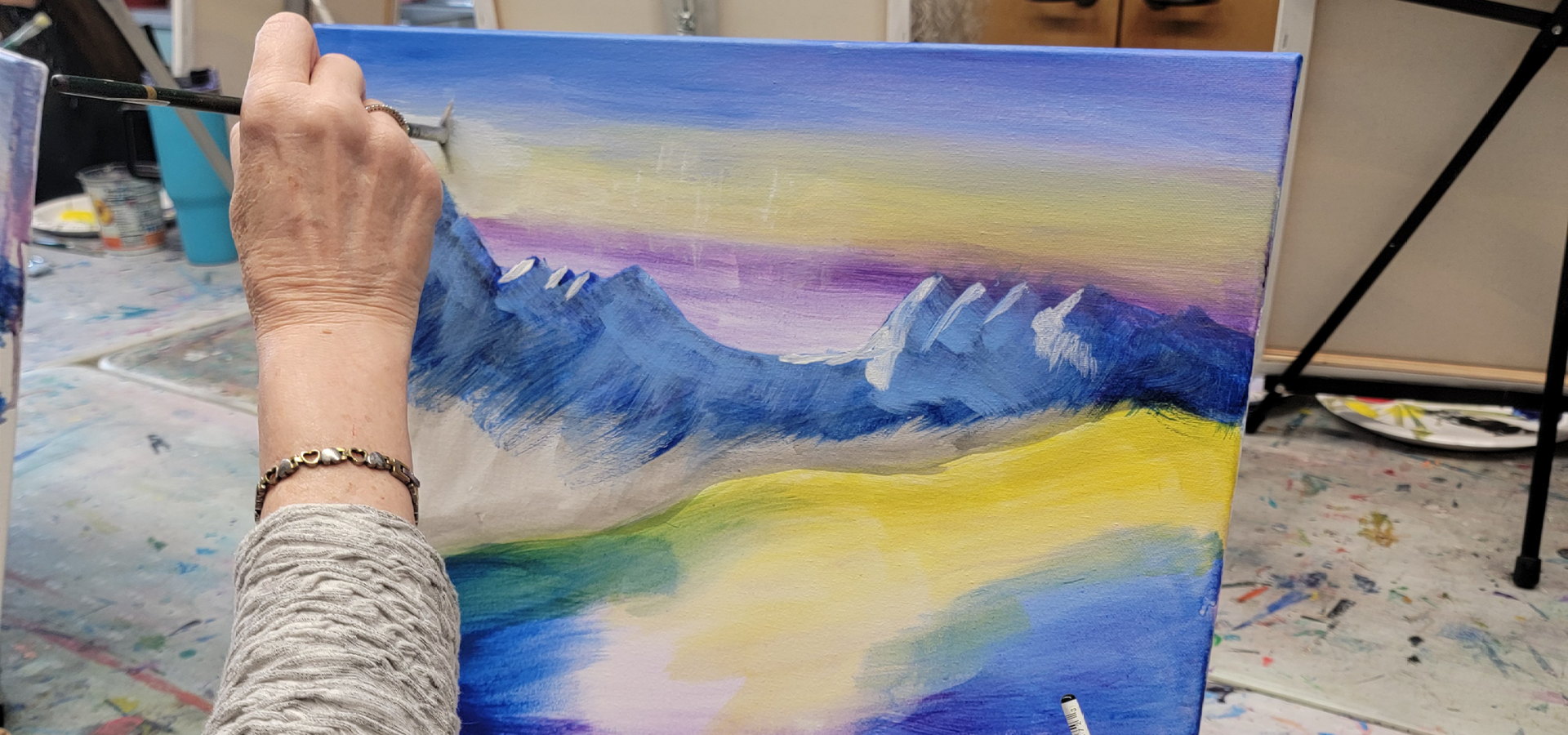 Close-up of a hand with paintbrush painting an alpenglow mountain artpiece