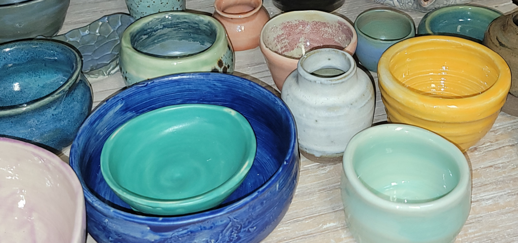 A variety of colorful finished clay pieces including bowls and vases