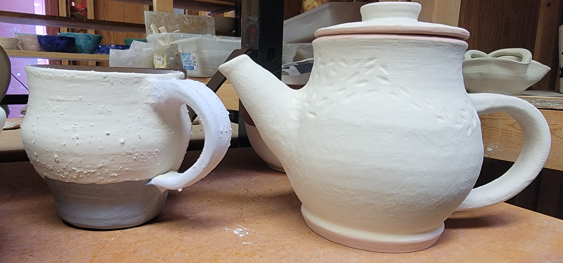 Unfinished tea pot and mug await finishing in the kiln