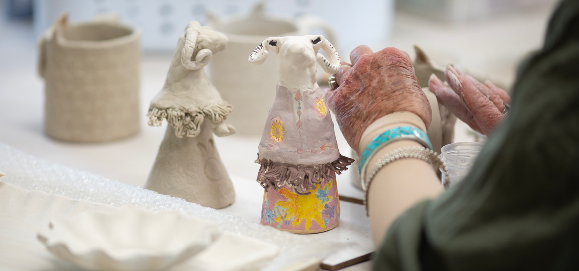 Close-up of adult hands working on a handbuilt clay artpiece