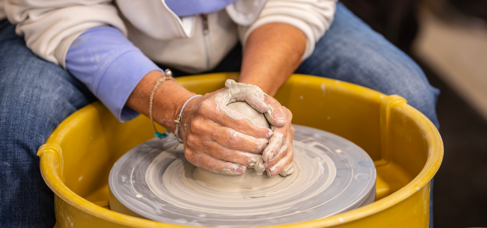 Close-up of an adult's hands molding clay on the pottery wheel