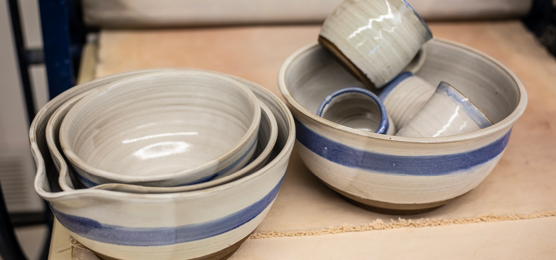 Finished, kiln-dried pottery bowls and mugs colored gray-brown with blue stripes