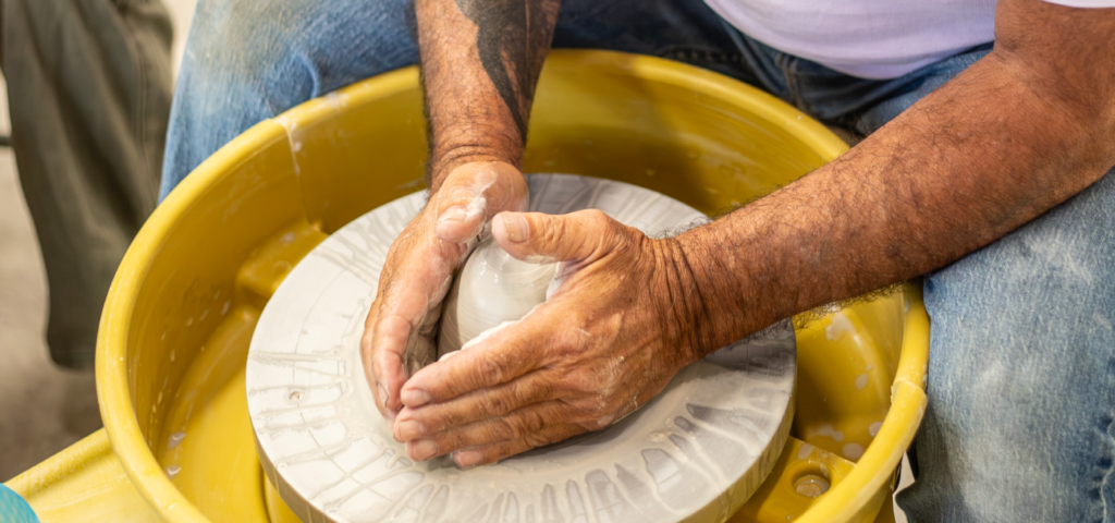 Close-up of an adult's hands molding clay on the pottery wheel