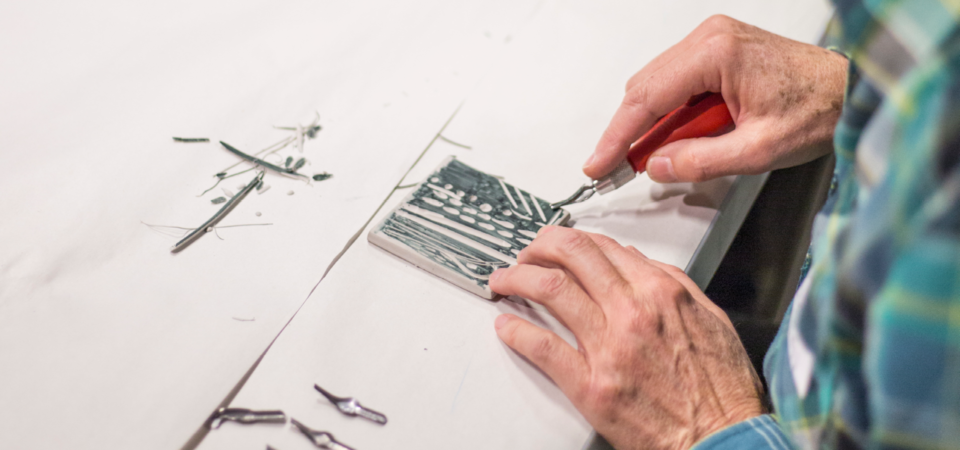 Close-up of two hands as a person carves linoleum in a printmaking class