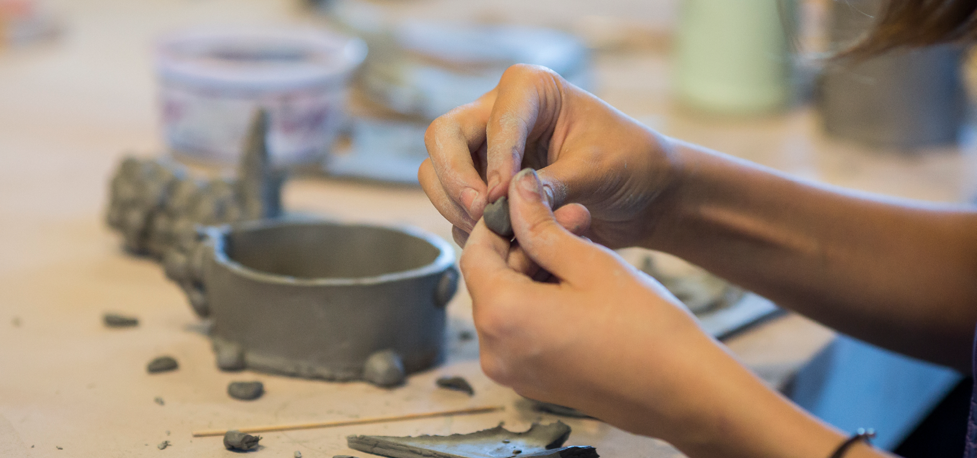 Close-up on hands manipulating clay in a handbuilt pottery class