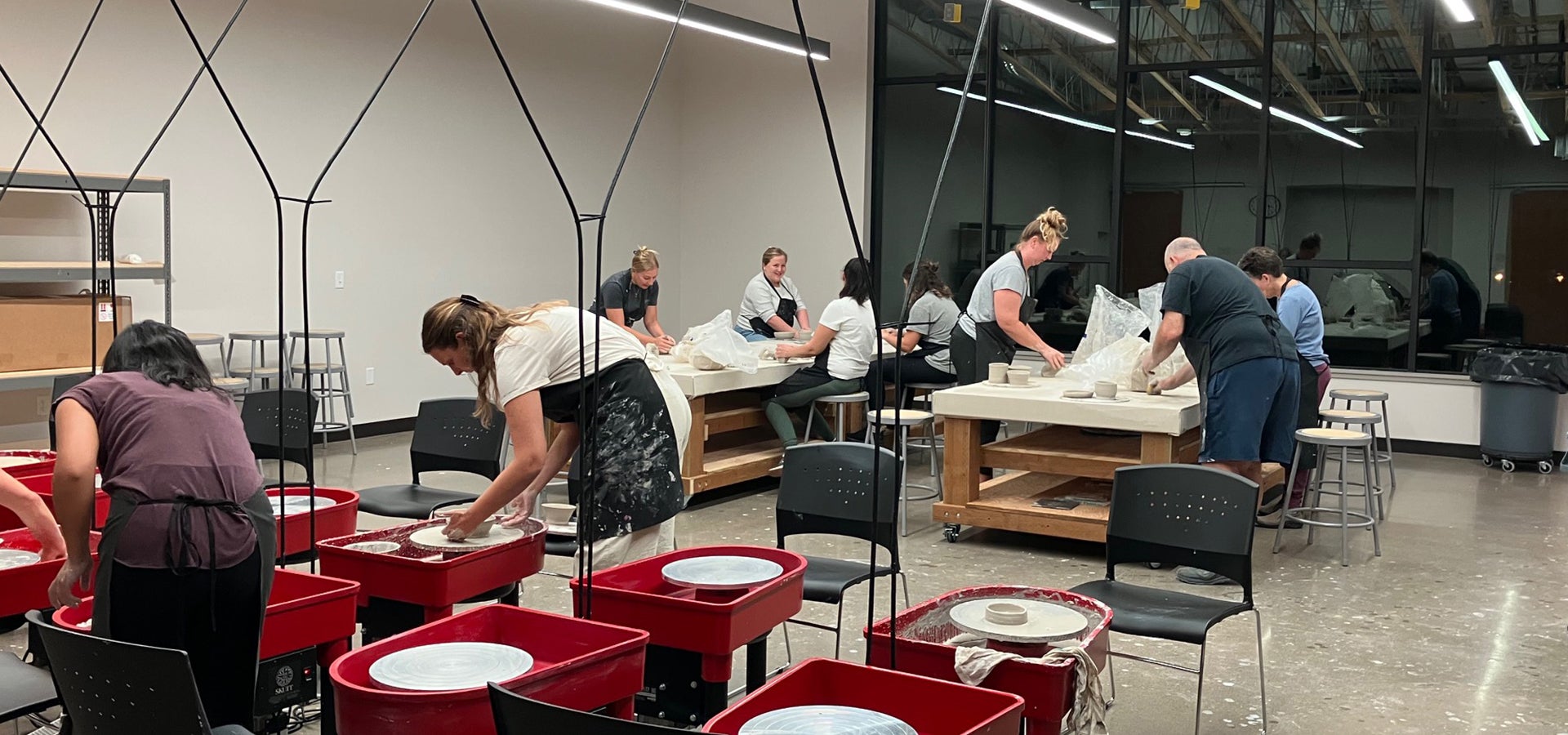 clay studio with wheels and work tables with group of artists working in a class