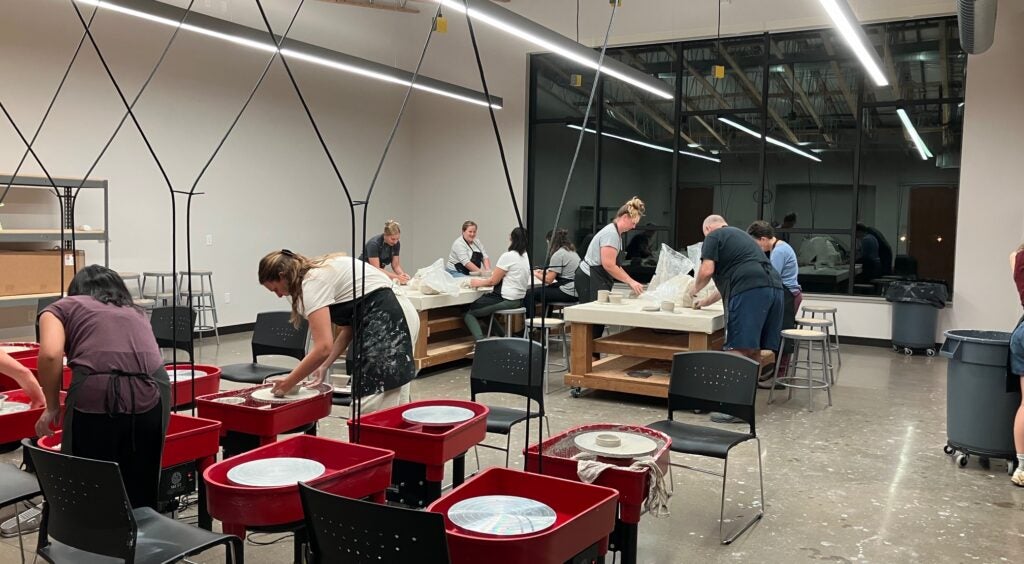 Artists at work in the clay studio with wheels and tables throughout the room