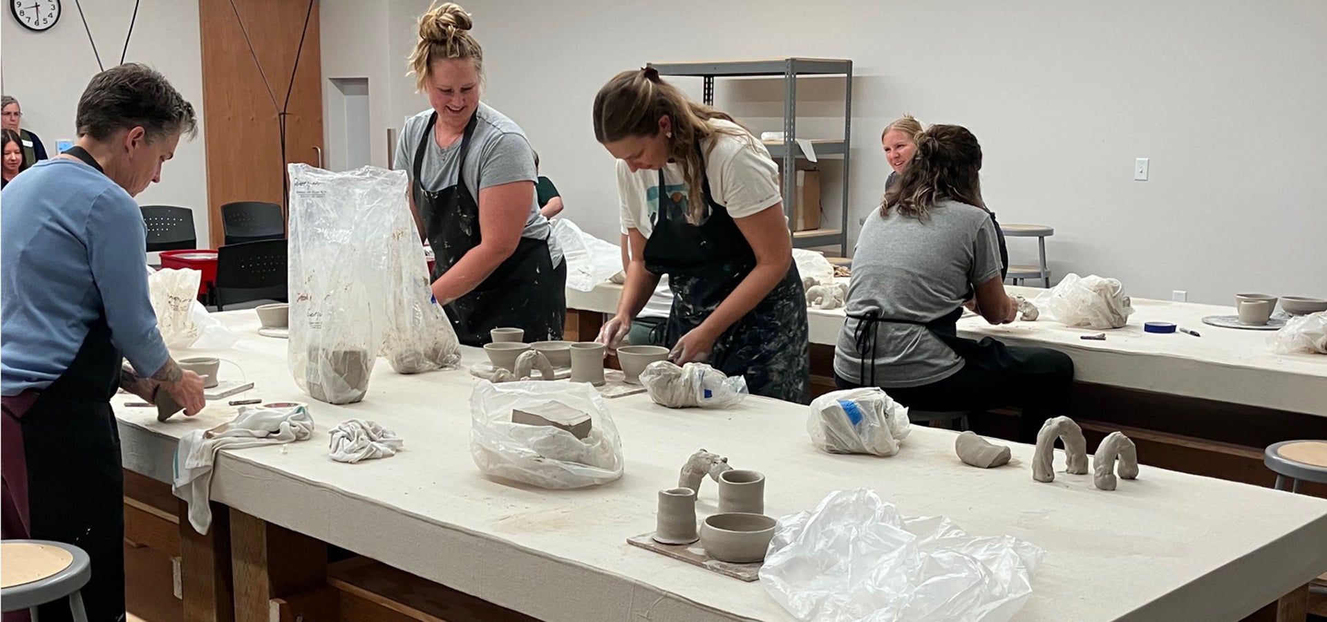 group of artists work on clay projects on tables in clay studio