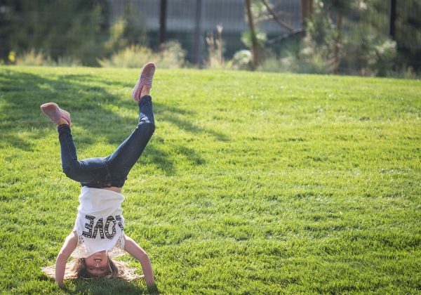 A kid doing a handstand in the grass.