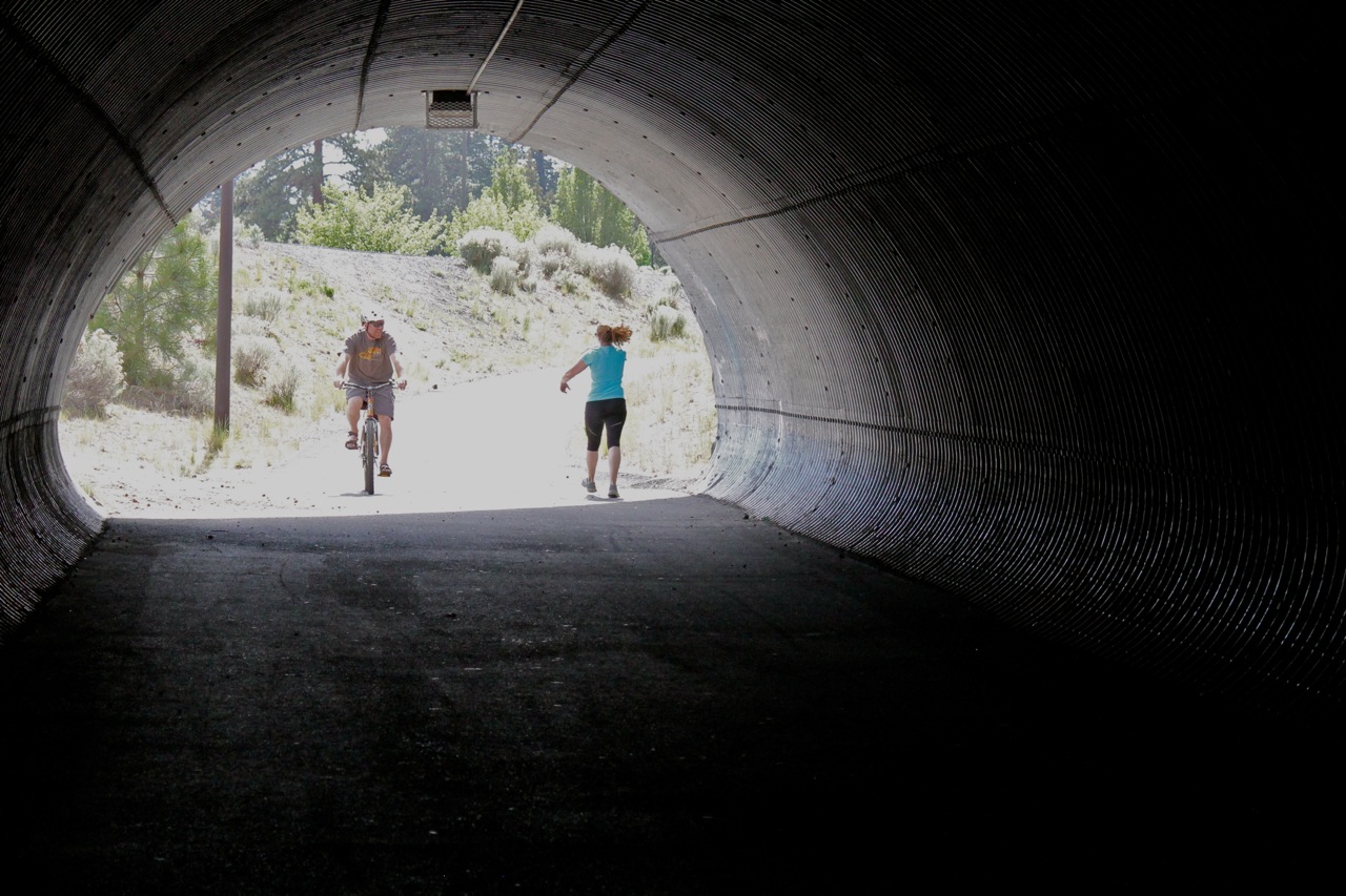 a man riding a bike and a woman walking through a tunnel on the larkspur trail