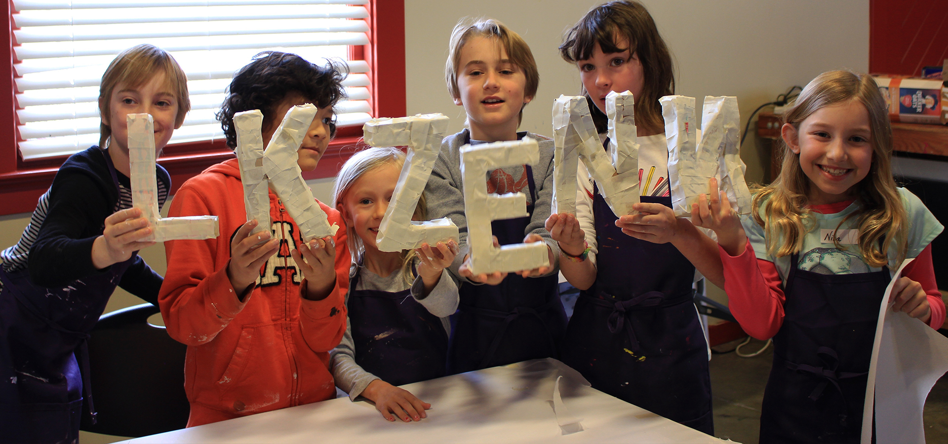 Kids showing off letter art at the art station.