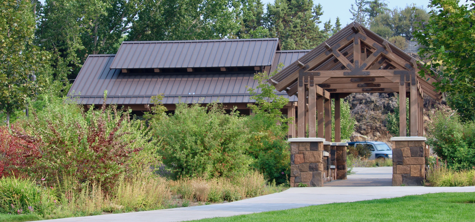 paved walkway leads into a small picnic shelter at Miller's Landing park with larger shelter in abckground
