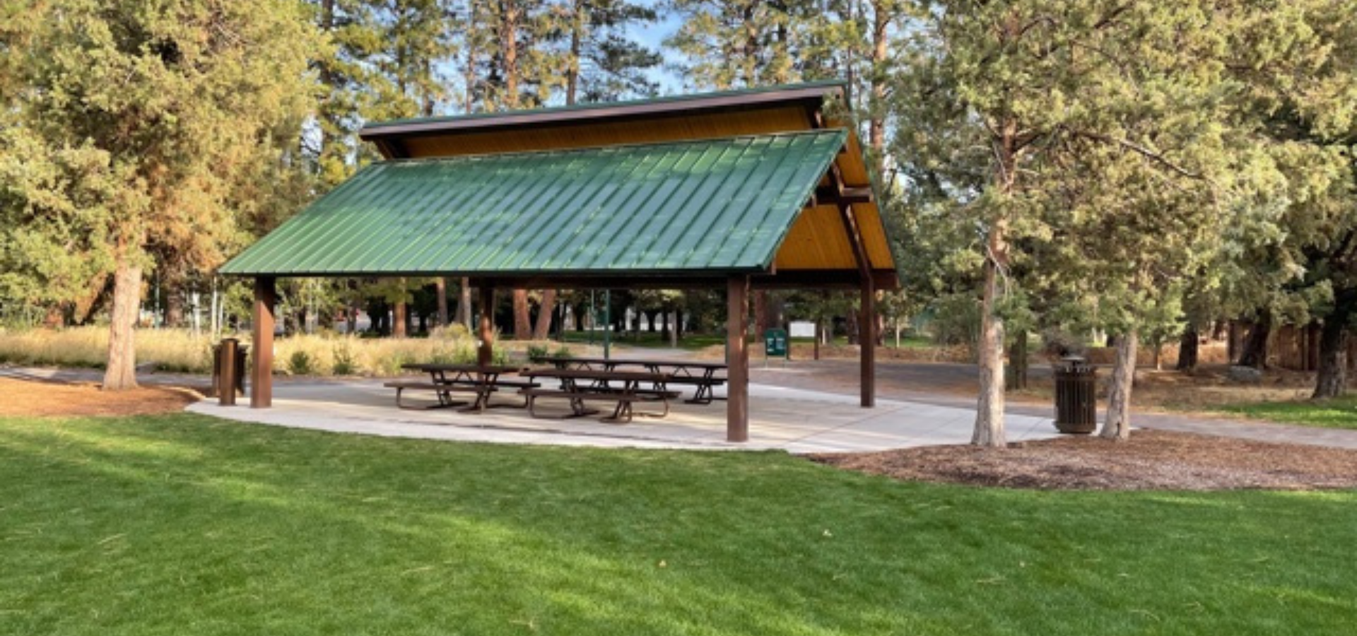 green lawn next to the picnic shelter at Larkspur park, flanked by trees