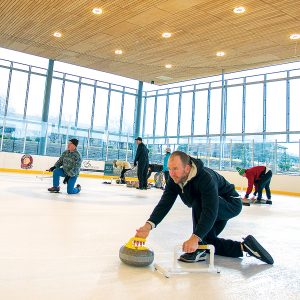 An Adult Curling League participant throwing a stone.
