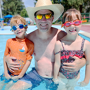 A man and two children posing at the pool.