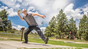 disc golfer letting go of disc on course