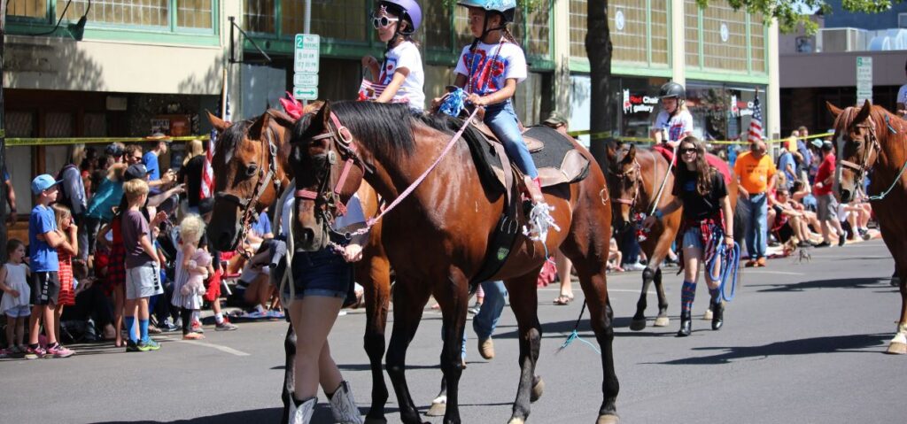 two kids on horses during pet parade