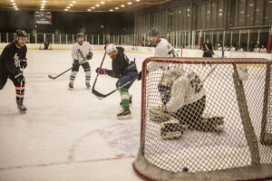 players battle for a loose puck in front of the net during a hockey game