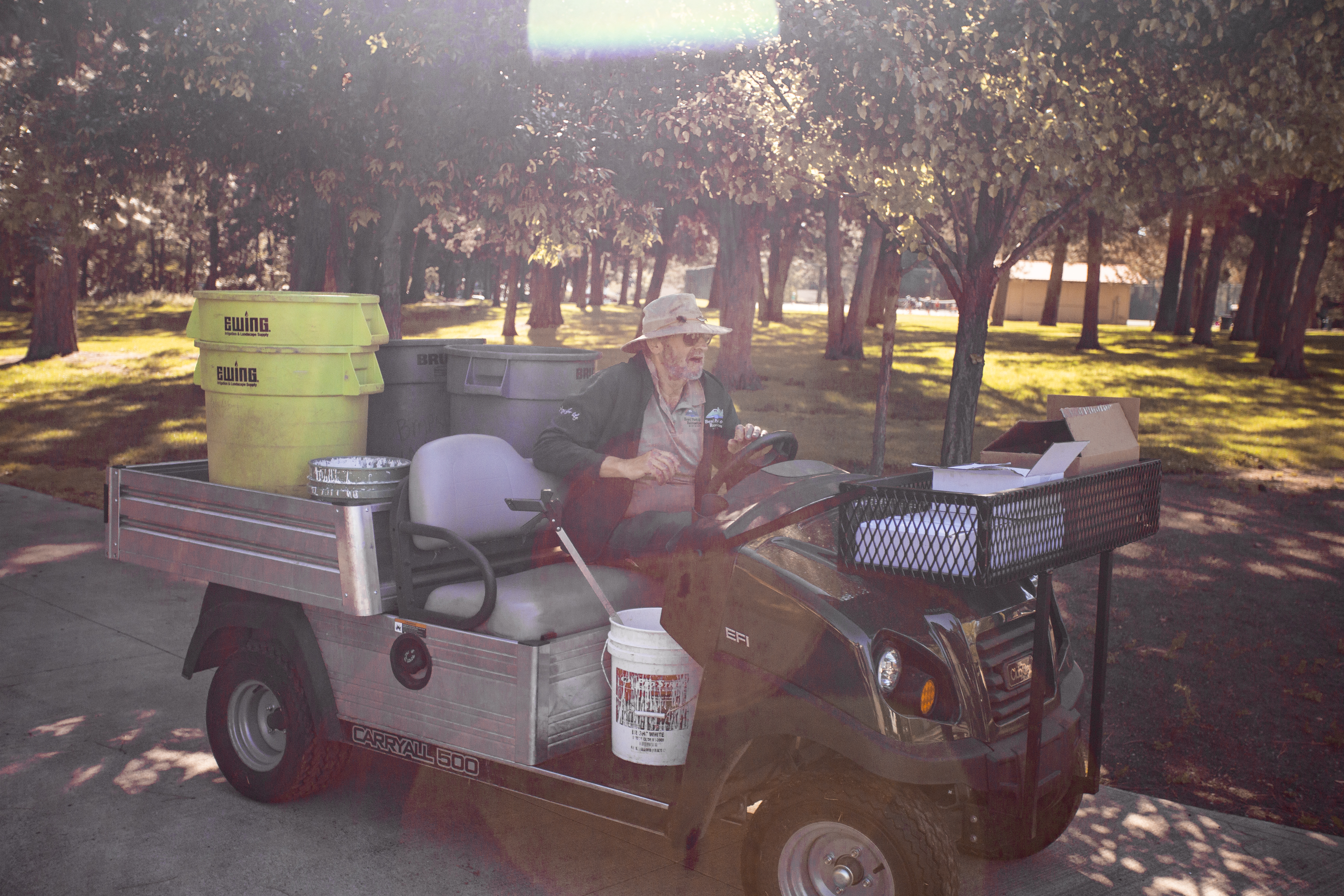 a landscaper drives a golf cart to another project