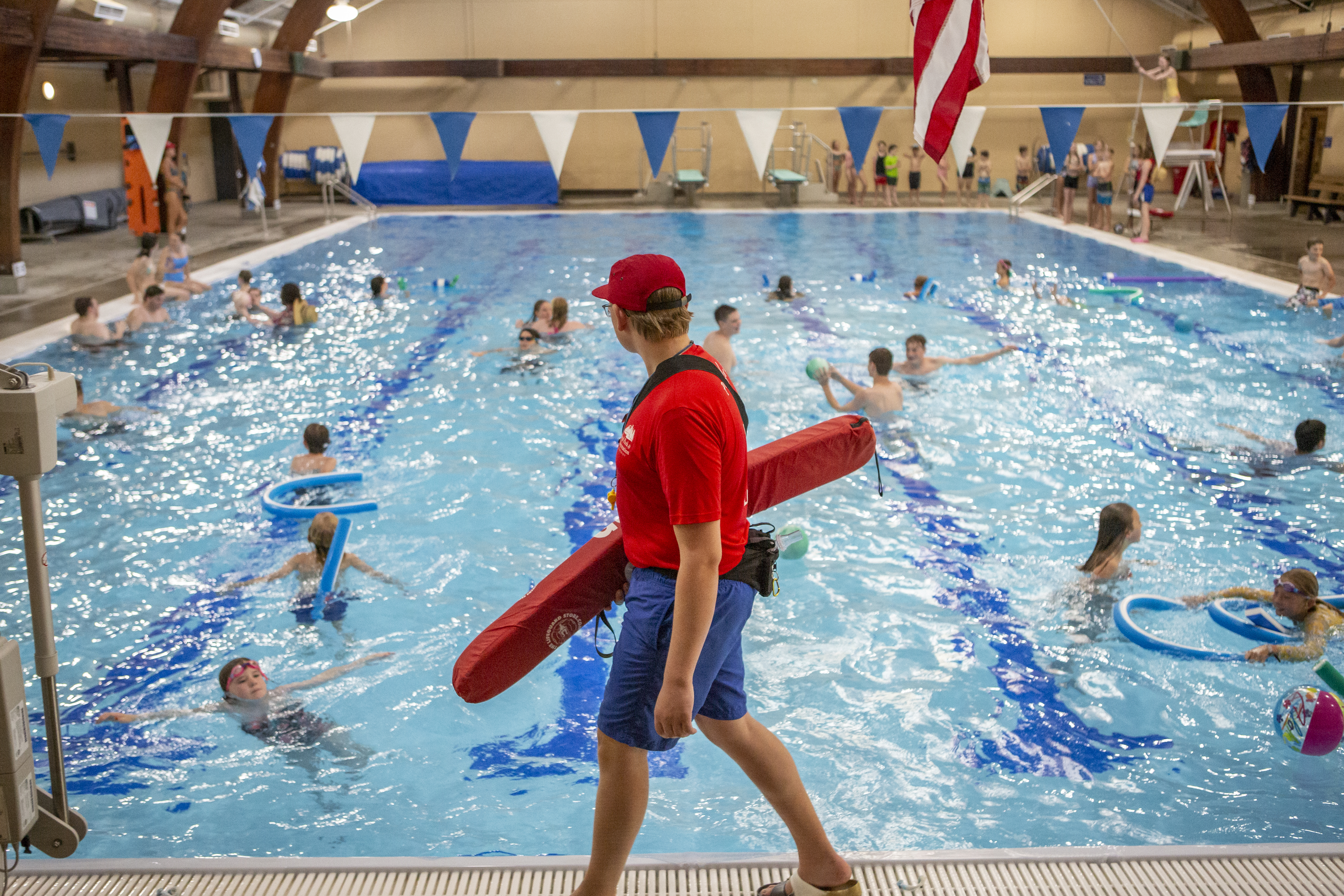 a male lifeguard patrols the pool deck at juniper swim and fitness center