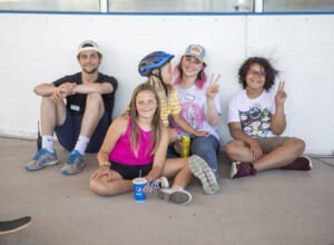 two youth recreation staff sitting with three kids