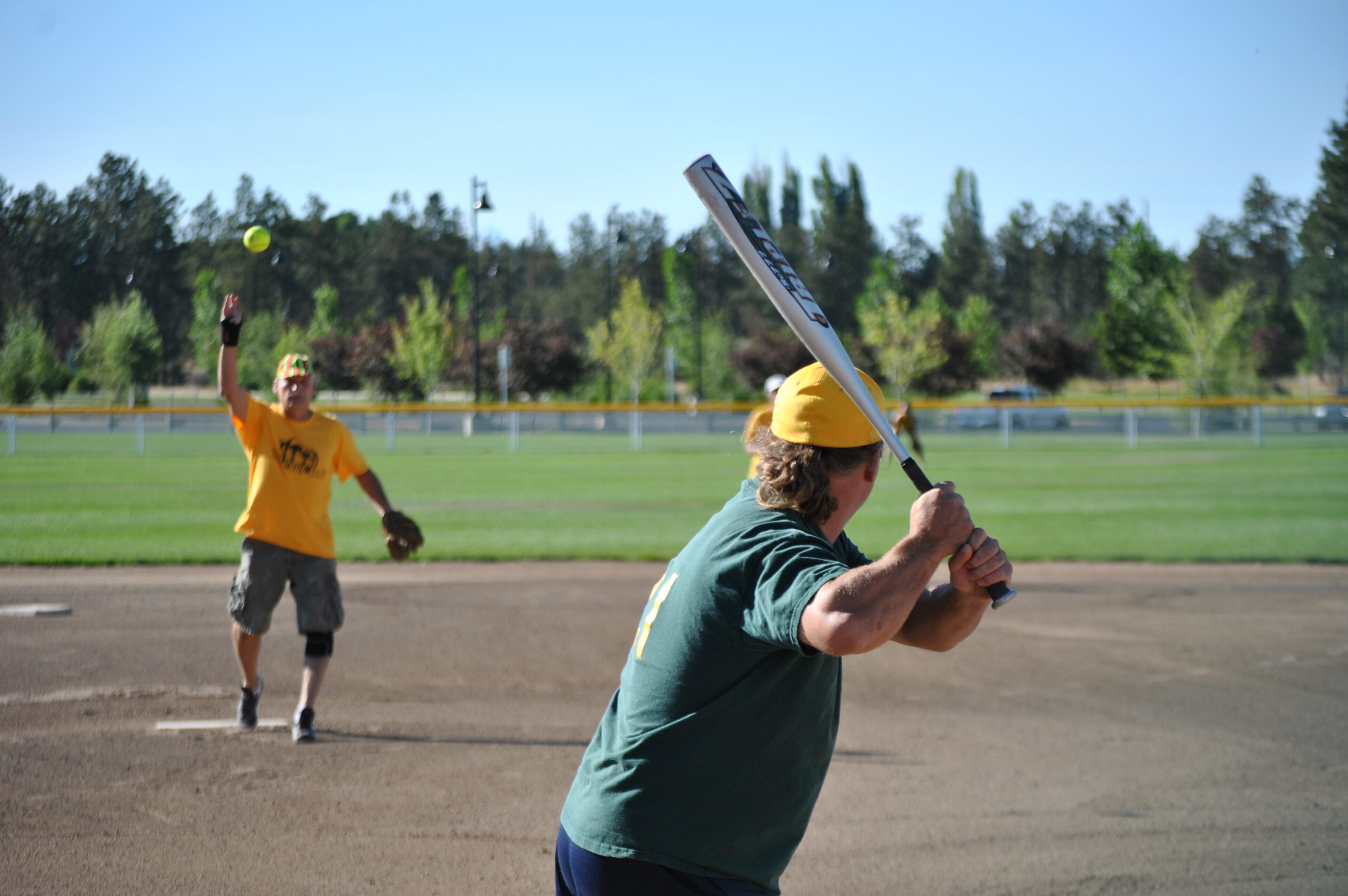 A slow pitch softball pitcher pitches a ball at pine nursery park