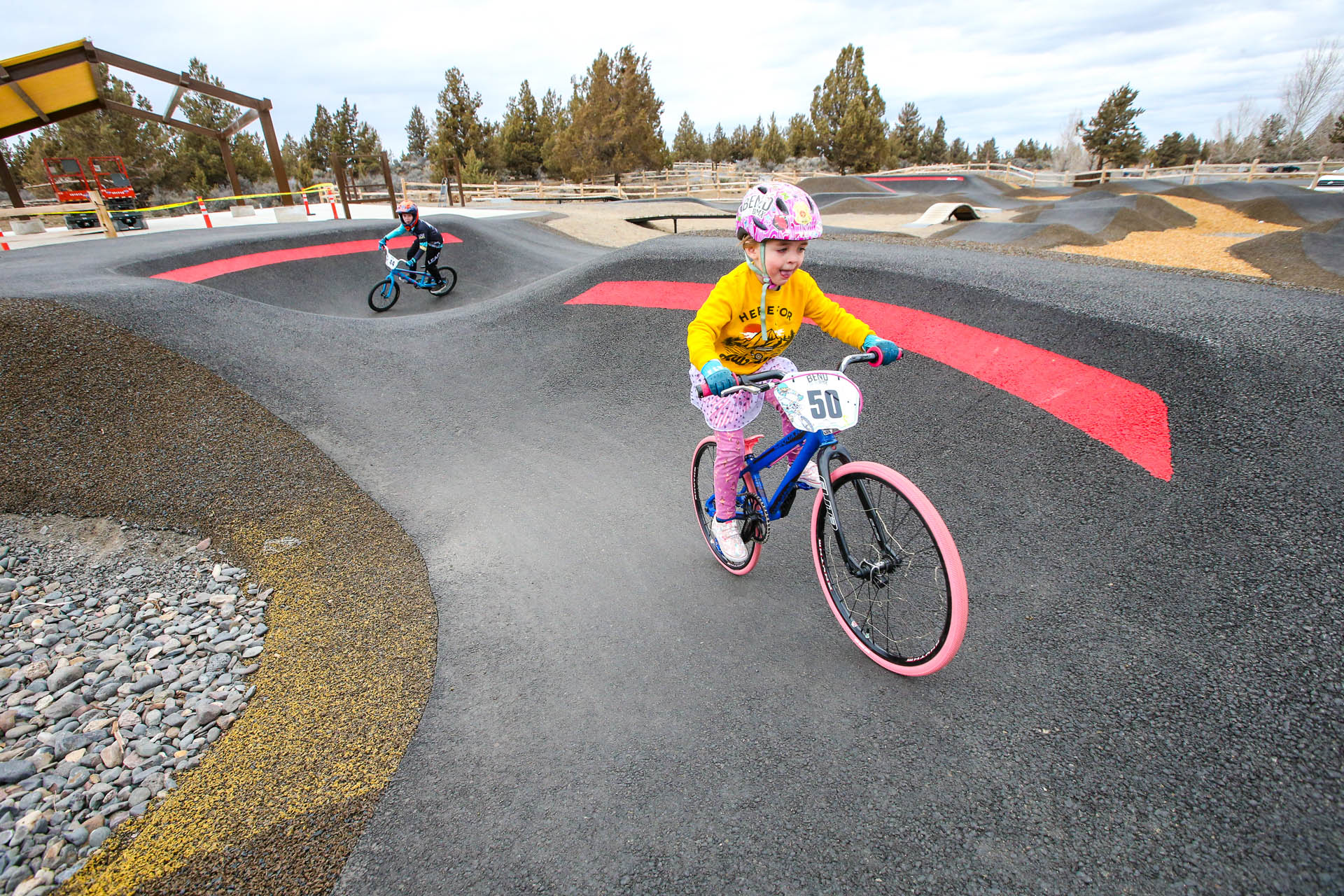 two young cyclists ride their BMX bikes on the pump track