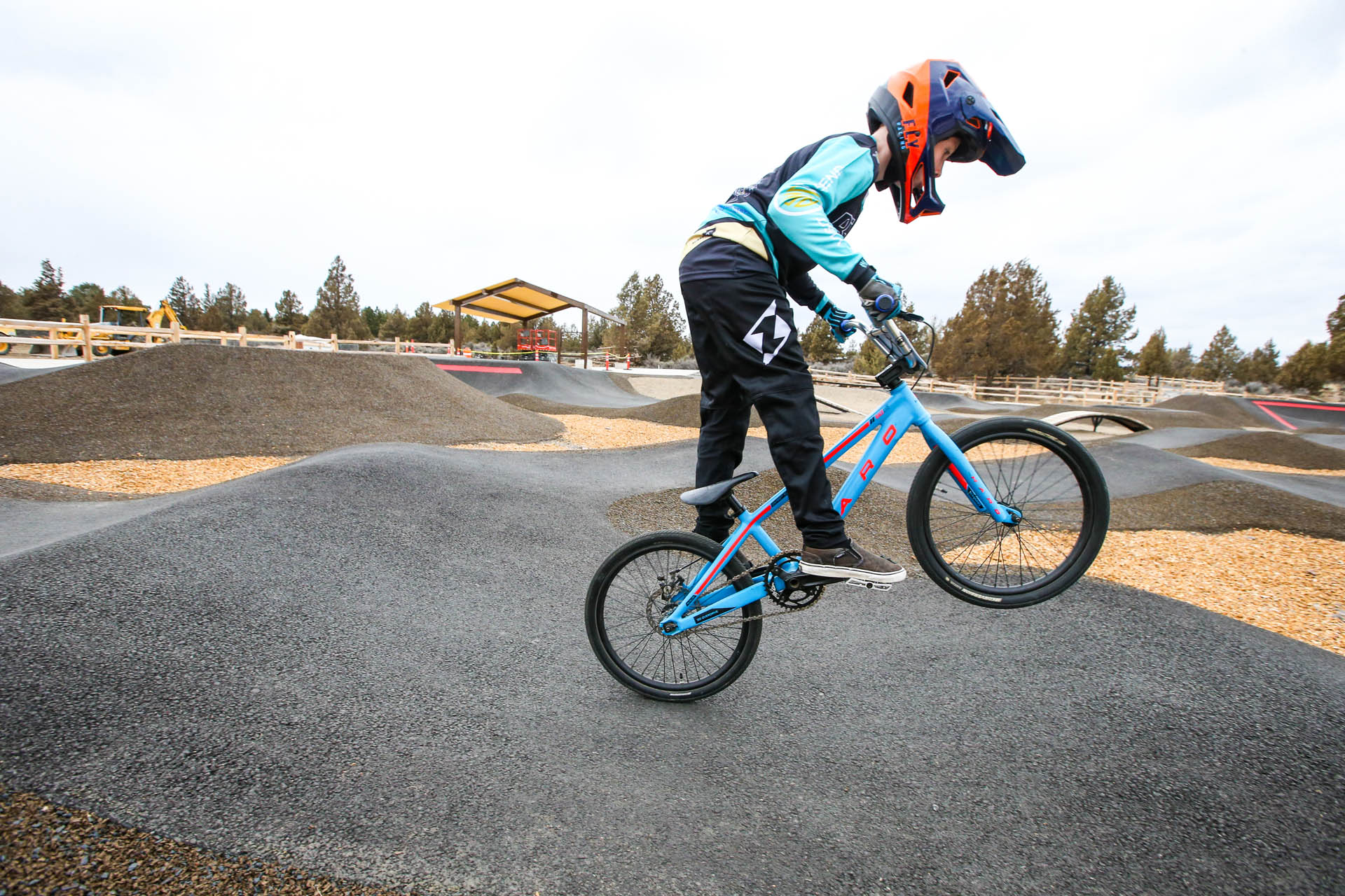 a young cyclist does a wheelie on a bmx bike on the pump track