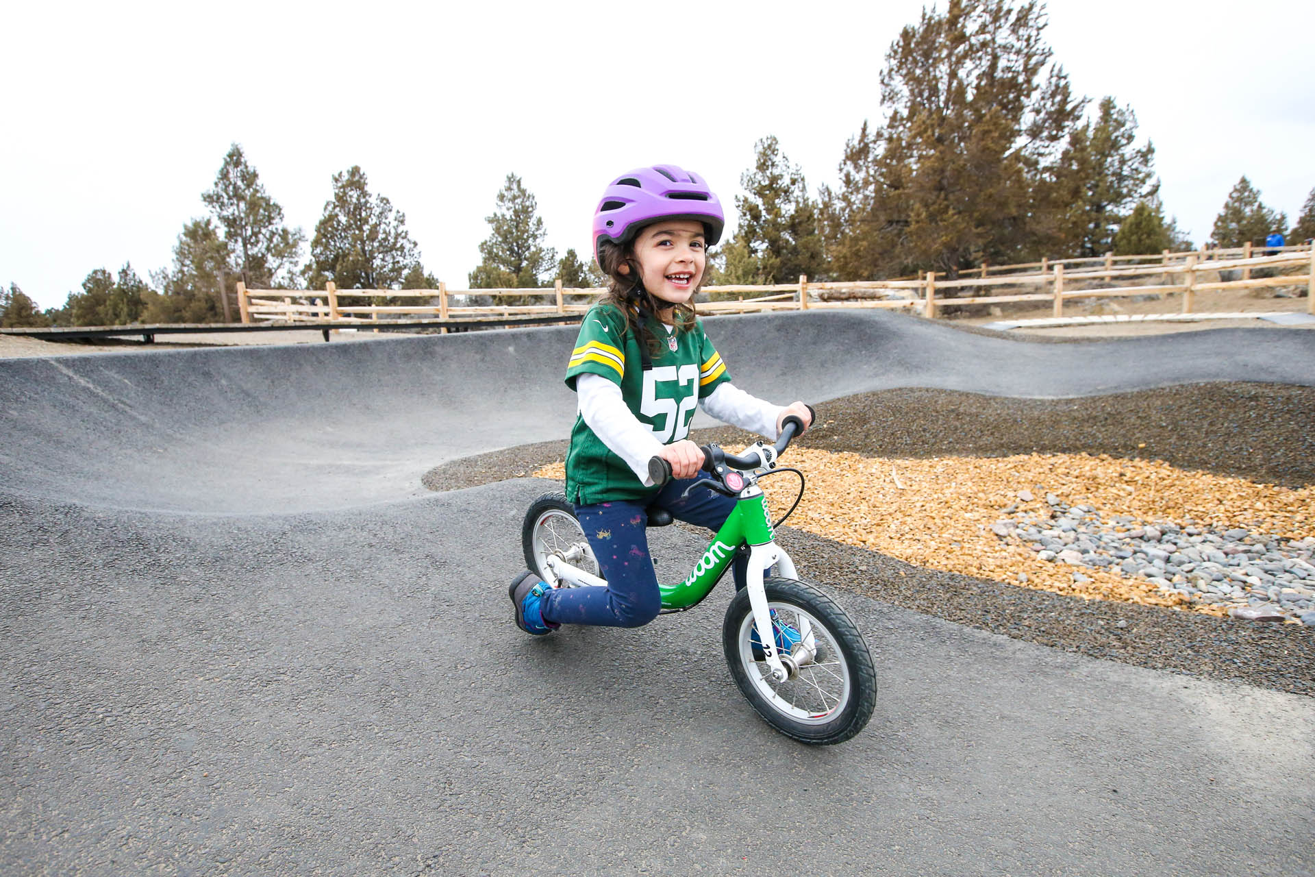 a young cyclist smiles while riding a scoot bike on the pump track
