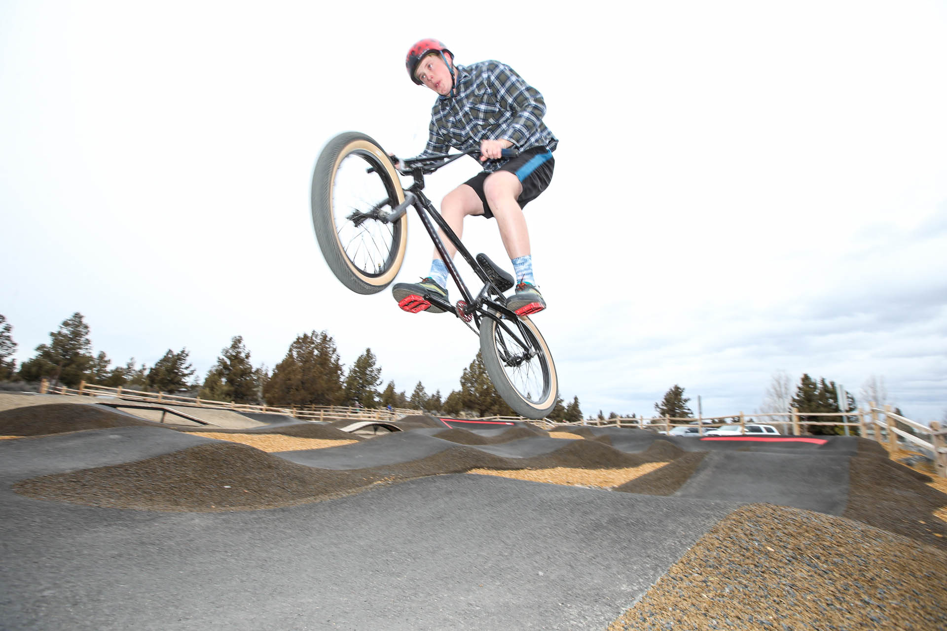 a cyclist on a BMX bike catches air on the pump track