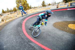 a cyclist rounds a turn on the arched corner of the pump track