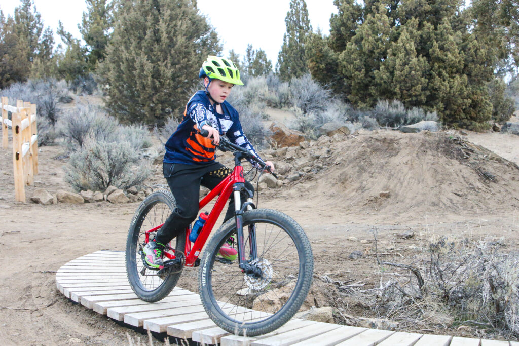 a child on a bike rides on the skills bike track with natural scenery in the background